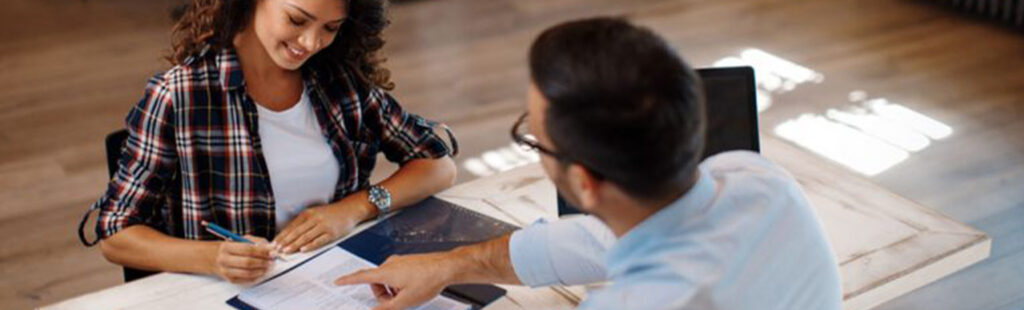 Signature d’un devis lors d’un rendez-vous commercial entre une cliente satisfaite et un conseiller professionnel.