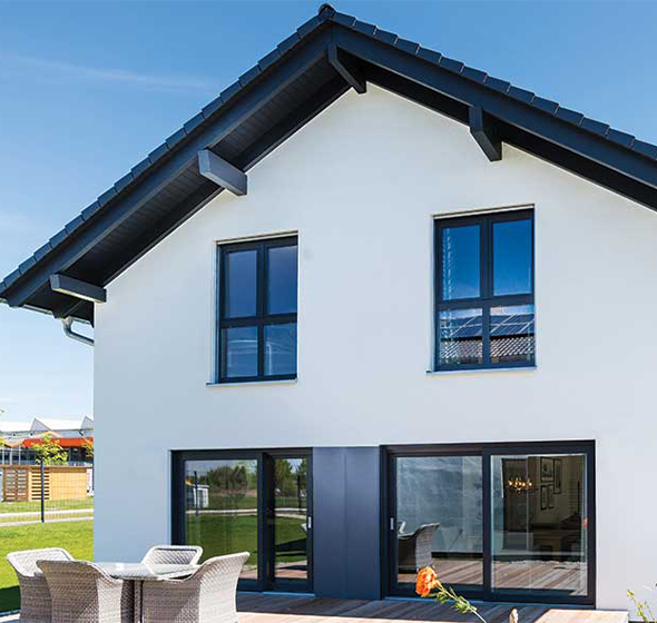 Façade moderne d’une maison blanche avec menuiseries aluminium noires donnant sur la terrasse