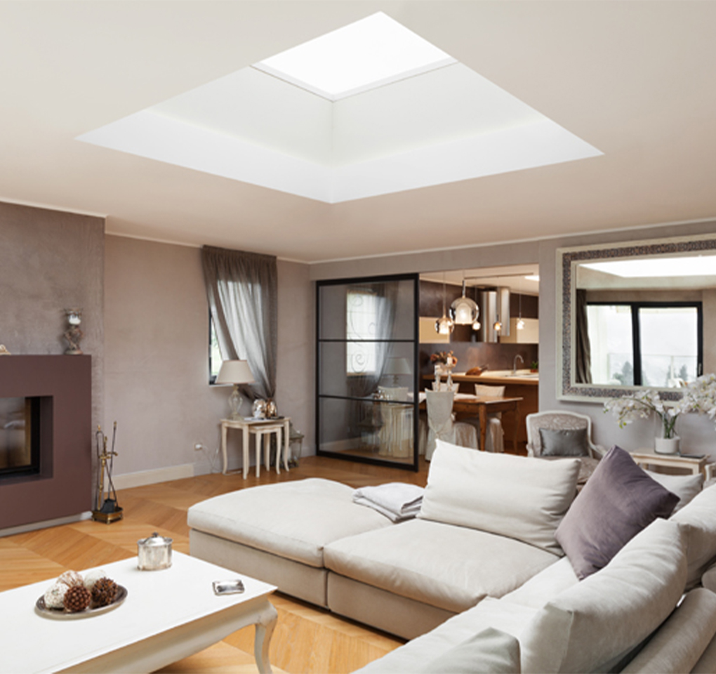 Salon élégant aux teintes brunes, blanches et prunes, avec une grande hauteur sous plafond et un large puits de lumière apportant une forte luminosité naturelle.