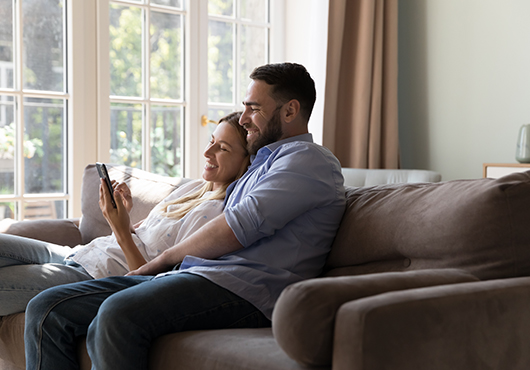 Couple heureux sur le canapé, devant une fenêtre blanche