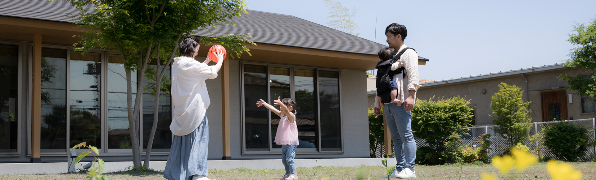 Famille qui joue au ballon dans le jardin de leur maison