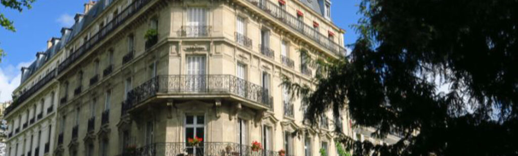Façade extérieure d'un immeuble parisien type haussmannien avec fenêtres à rénover