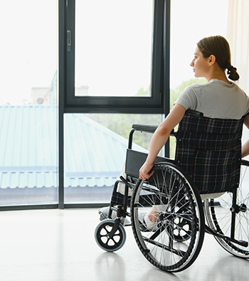 Femme en fauteuil roulant devant sa baie vitrée