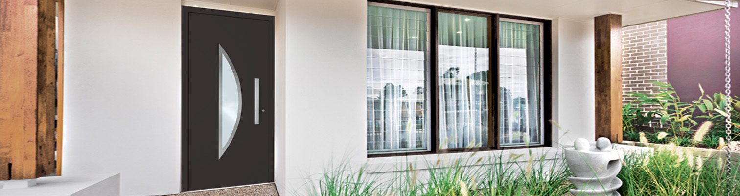 Zoom sur une façade de maison contemporaine avec une porte d'entrée aluminium partiellement vitrée grise anthracite Amcc