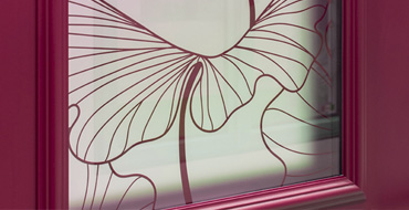 Zoom d'un détail de porte montrant un vitrage imprimé en couleur ral avec motif botanica et détails de moulures porte d'entrée modèle Alessia Prestige AMCC
