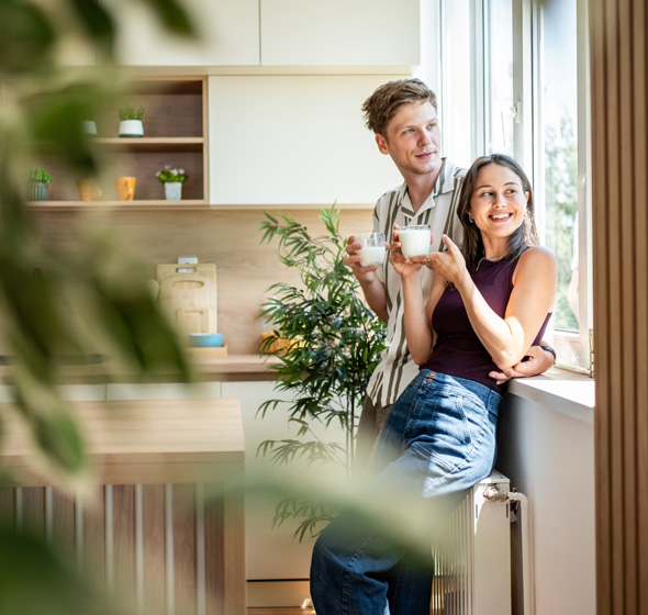 Jeune couple au petit déjeuner profitant de leur nouvelle fenêtres et de la luminosité intérieure