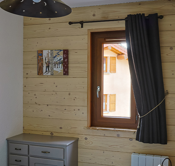 Fenêtre à un vantail en PVC effet bois AMCC, installée dans une chambre à coucher d'une habitation de montagne à Aussois.