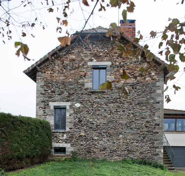 Maison traditionnelle du Cantal, en pierre grise locale, équipée des fenêtres Alya Exclusive d’AMCC, en gris anthracite.