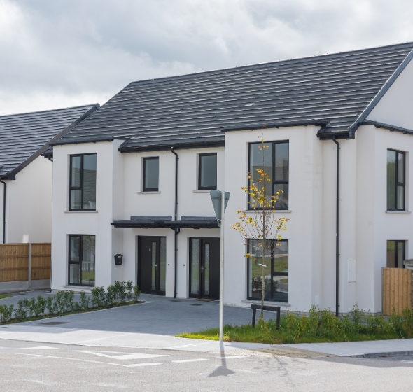 Une maison située dans un lotissement, avec une porte d’entrée semi-vitrée.